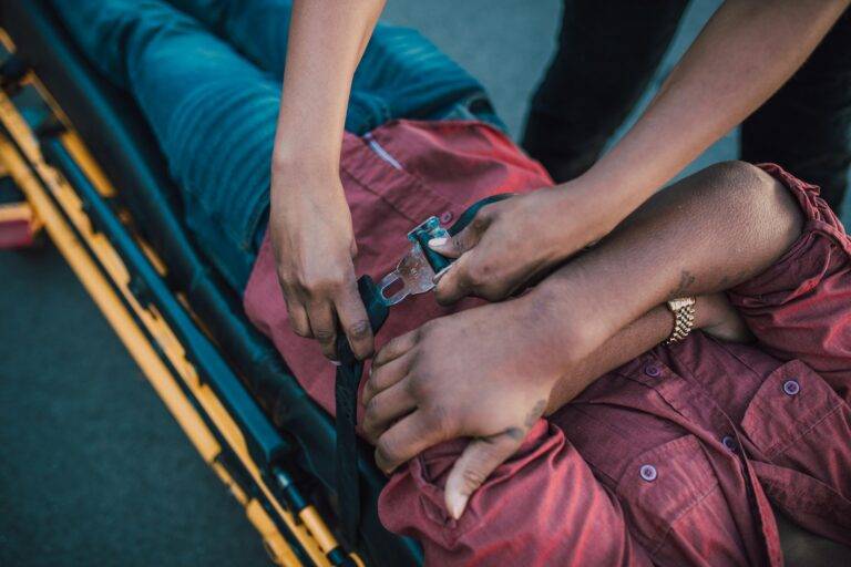 Close-up of a person securing an injured individual on a stretcher, providing emergency care.