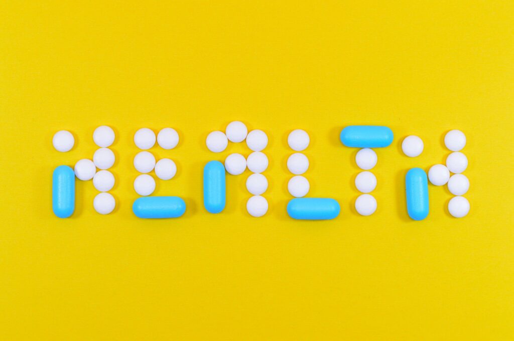 Pills spelling 'health' on a vibrant yellow background, symbolizing wellness.