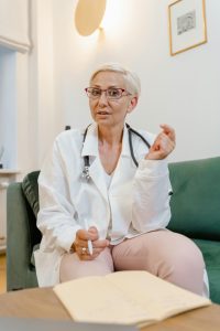 Senior female doctor with eyeglasses and stethoscope sitting indoors for consultation.